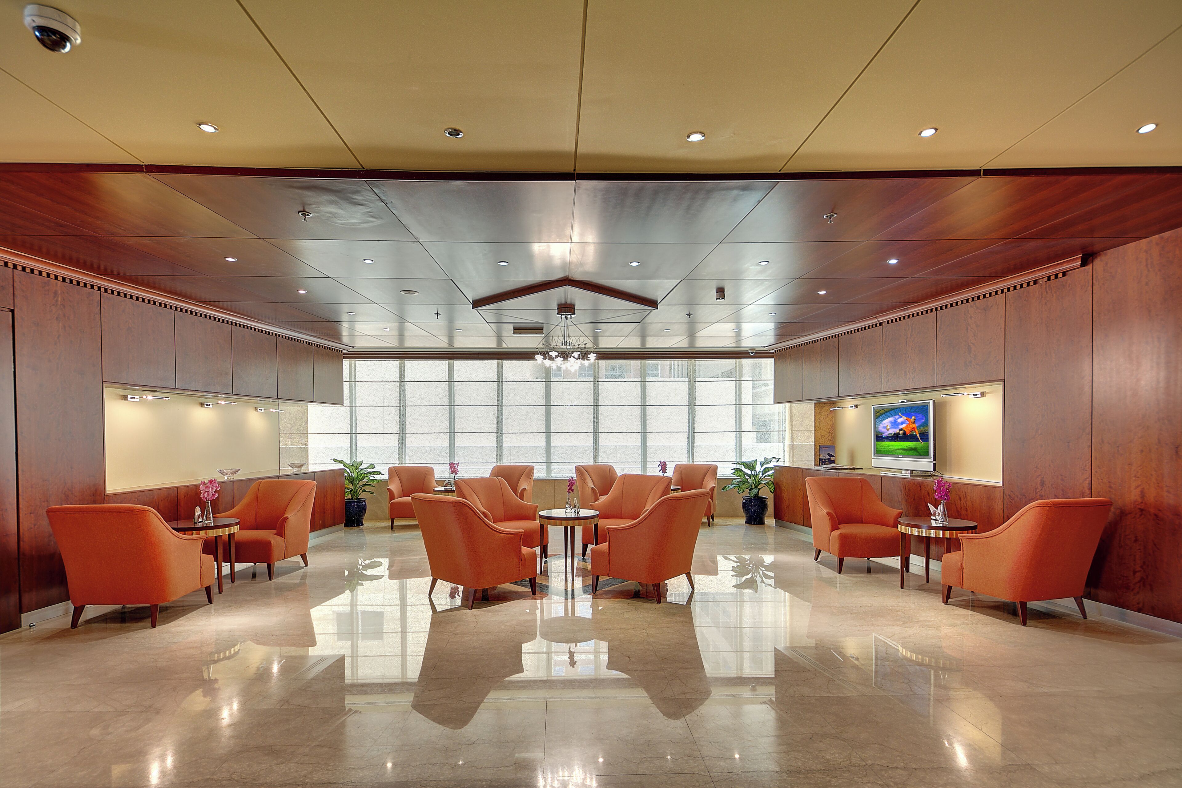 A spacious lobby with a high ceiling, modern lighting, and a large window providing natural light.