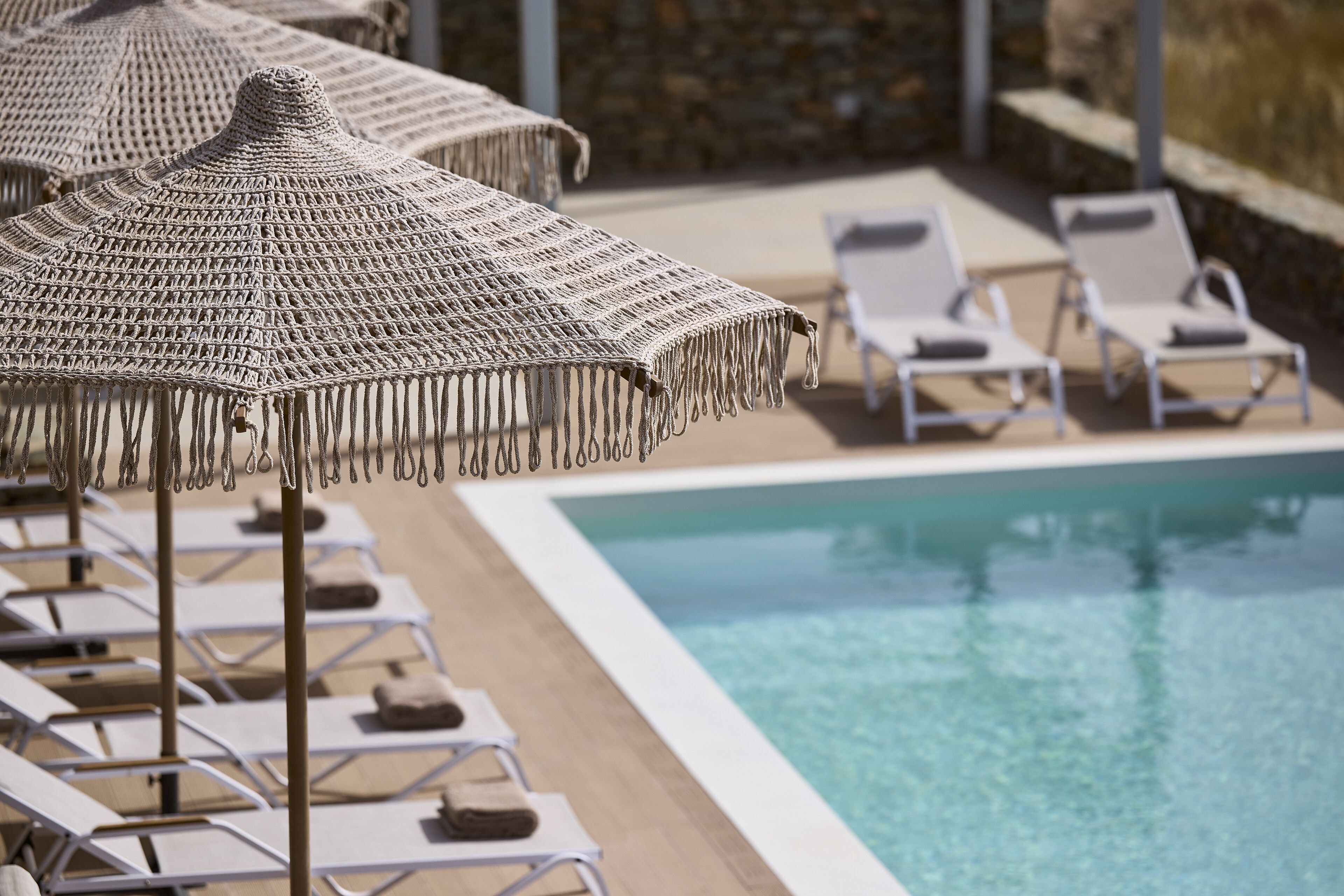 Zona de piscina amb gandules i ombrelles de fibra.