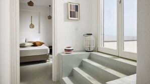 A bedroom with a bed, a window, and a staircase. - Ianemi Suites by K4 Kythnos (Kithnos)