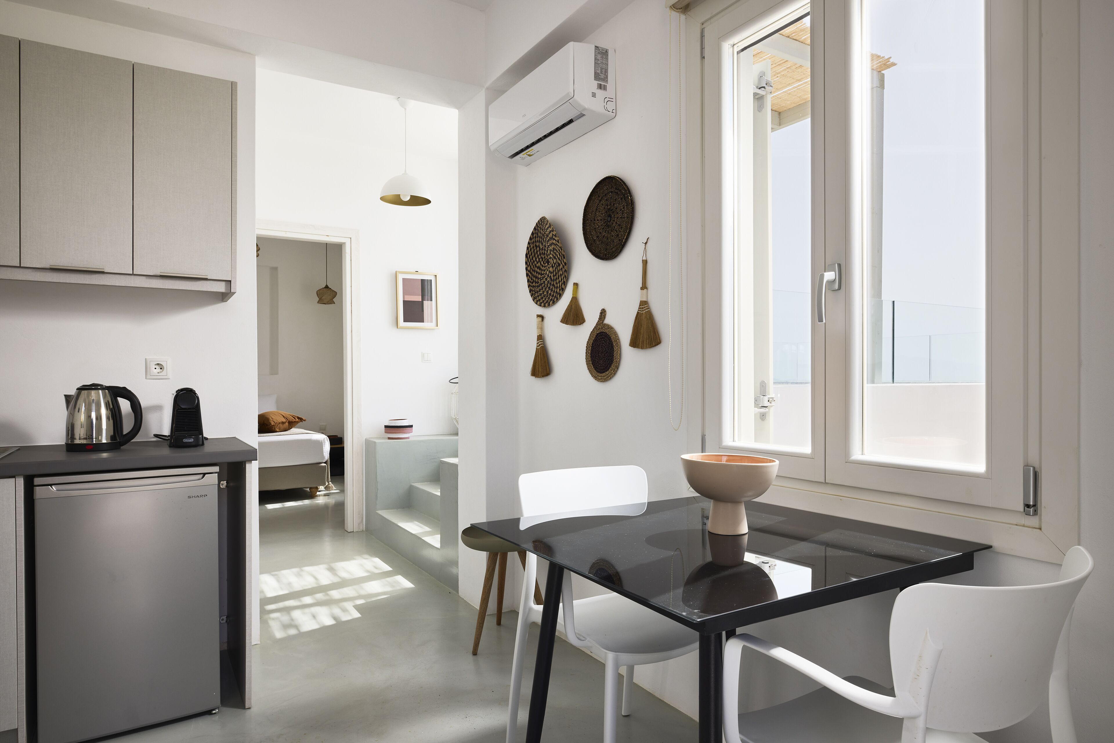 A modern kitchen with a refrigerator, a dining table with chairs, and a window with a view.