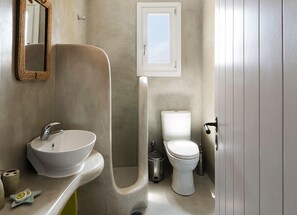 Une salle de bain avec un lavabo blanc, des toilettes et un miroir.
