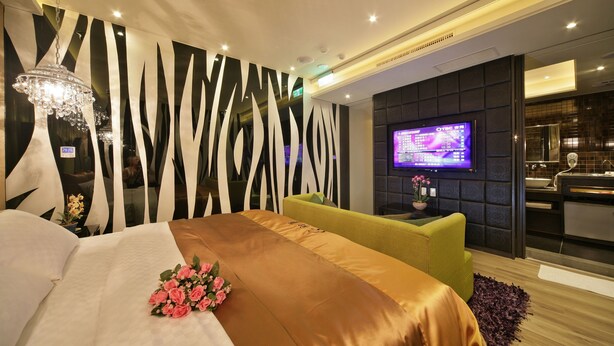 Ein modernes Hotelzimmer mit einem großen Bett, einem Fernseher und einem Badezimmer mit Spiegel und Waschbecken.