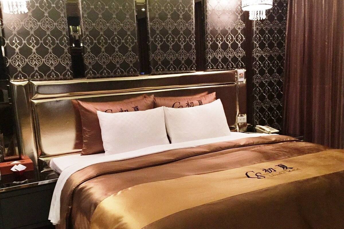 A hotel room with a bed, nightstand, and a decorative wall.