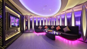 Ein stilvoller Lounge-Bereich mit einer gebogenen Couch, einem Couchtisch und einem an der Wand montierten Fernseher.