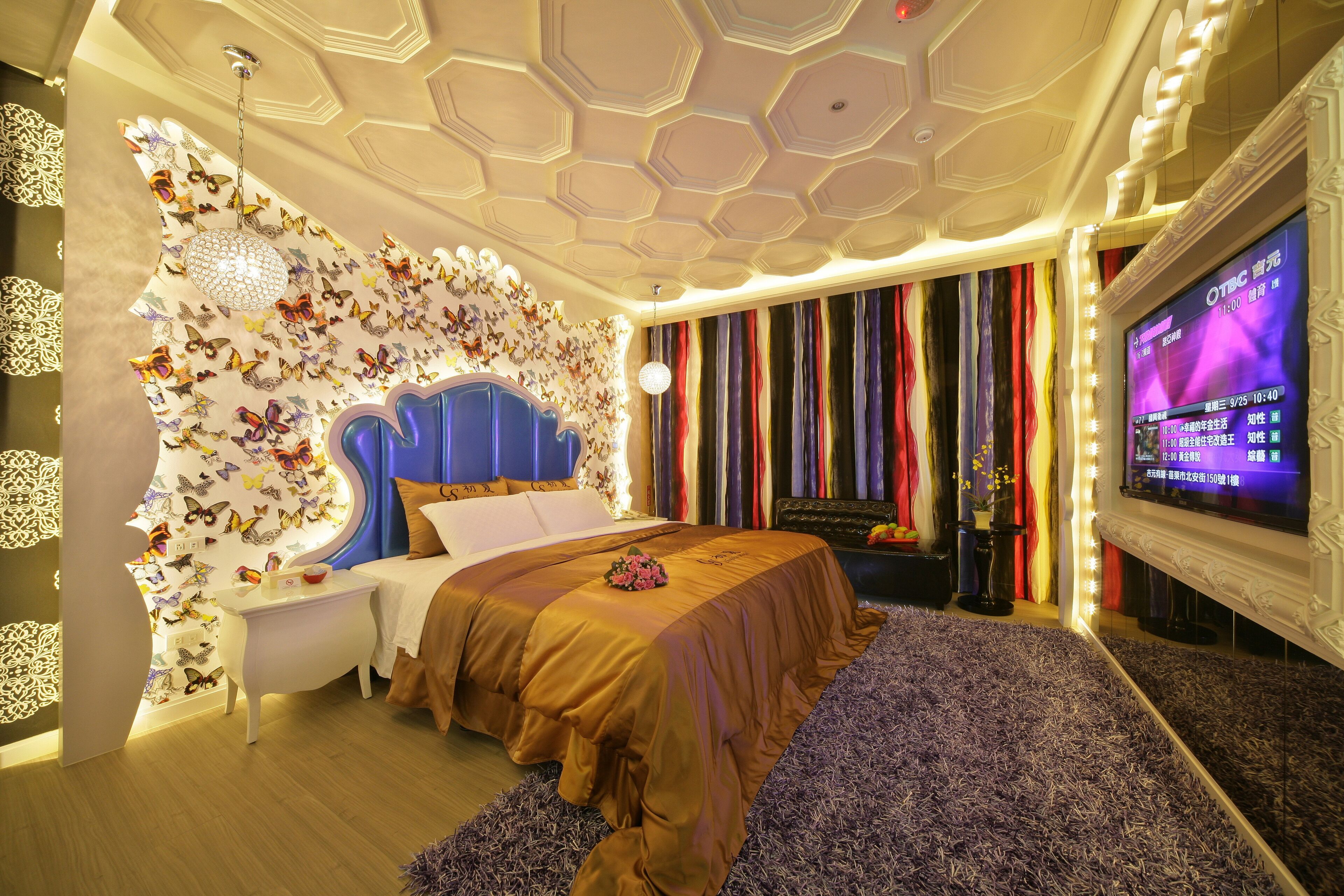 Un dormitorio moderno con una cama grande, un televisor y una pared decorada con mariposas.
