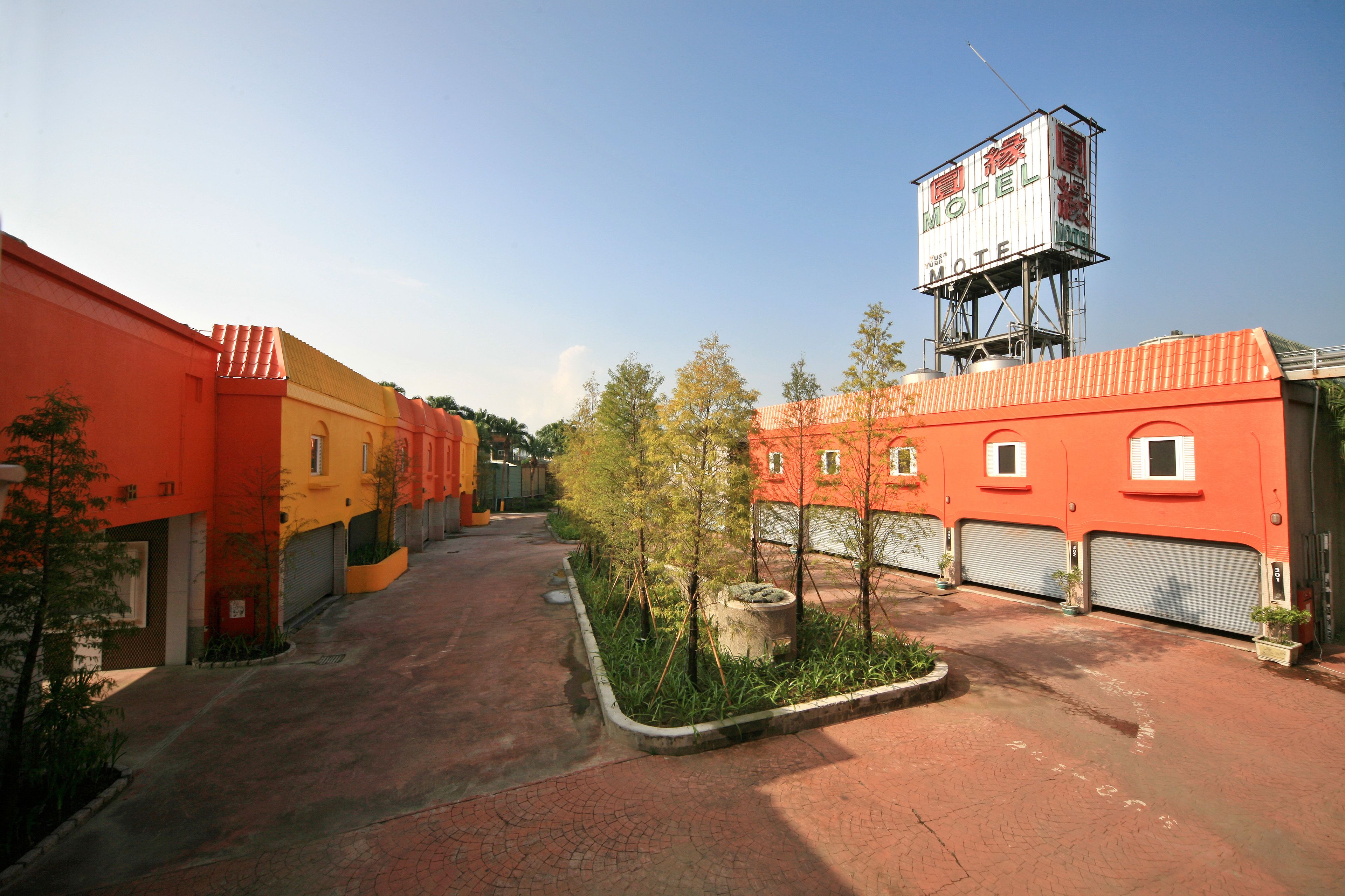 A motel with a large billboard, a parking lot, and a row of orange buildings.