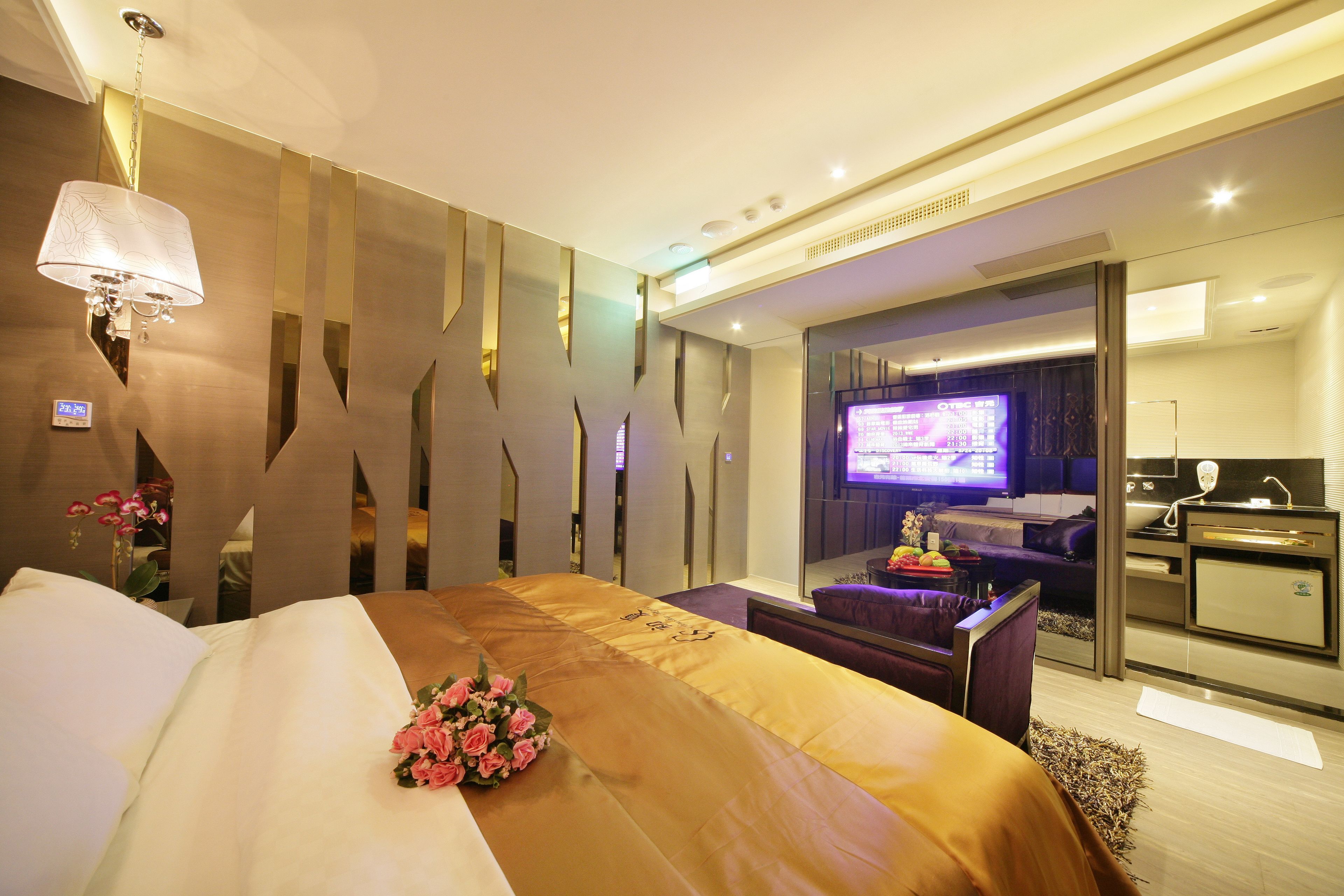 Une chambre d’hôtel moderne équipée d’un grand lit, d’une télévision, d’un bureau et d’une kitchenette.