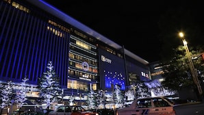 A modern building with a prominent clock and signage for "HAKATA STATION".