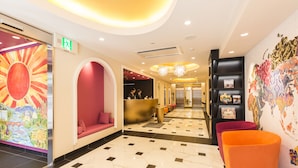 A hotel lobby with a reception desk, seating areas, and a decorative mural.