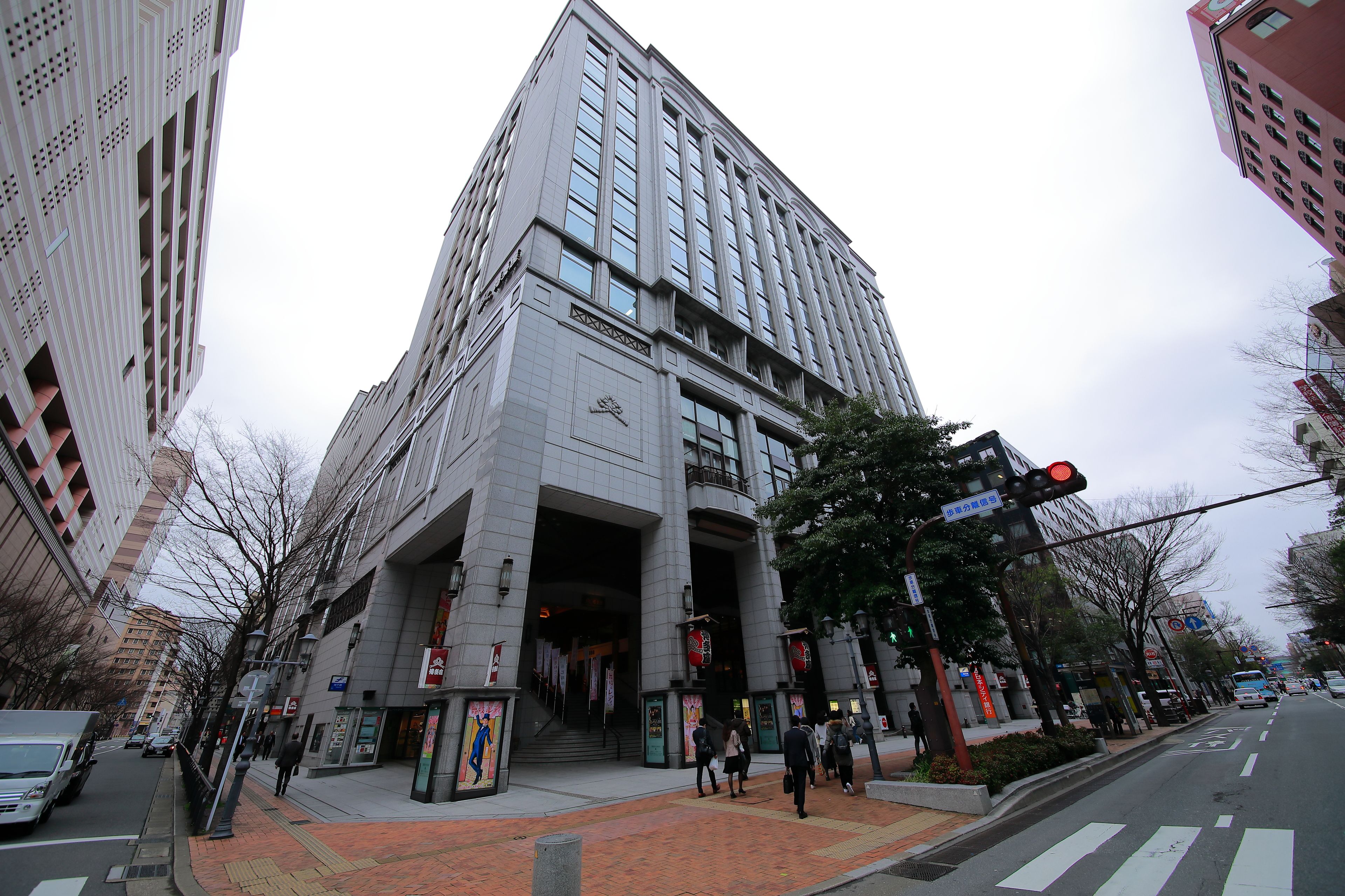 A multi-story building with a prominent entrance, large windows, and a red brick pathway leading to the entrance.