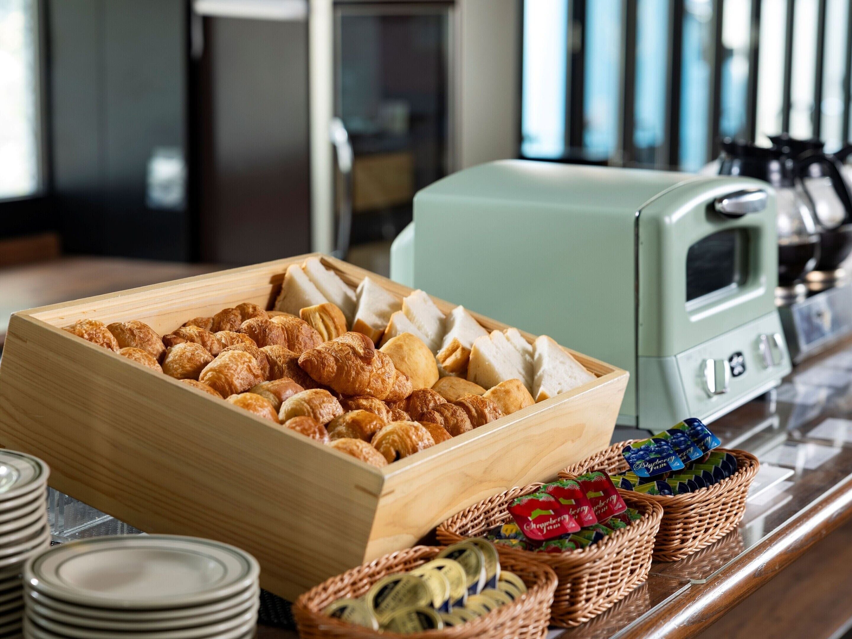 A buffet with a variety of pastries and bread, a vintage toaster, and baskets of fruit.