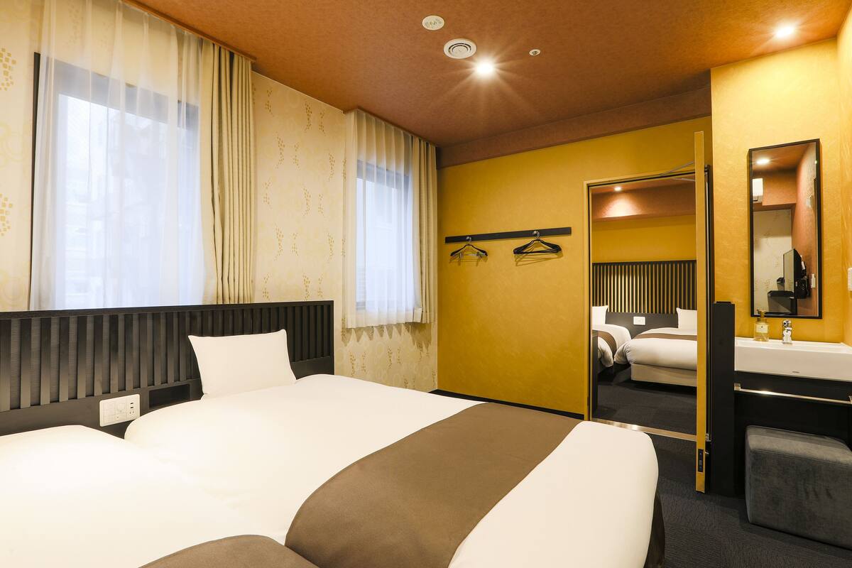 Habitación de hotel con una cama grande, una mesita de noche, un espejo y un baño con lavabo y toallero.