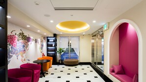 A lobby with a modern design, featuring a world map mural, a seating area with a pink sofa, and a small table with chairs.