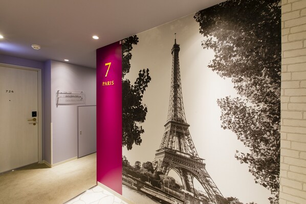 A hallway with a large mural of the Eiffel Tower, a door labeled "7 PARIS", and a sign indicating room numbers. - KOKO HOTEL Hakata Station (Fukuoka)