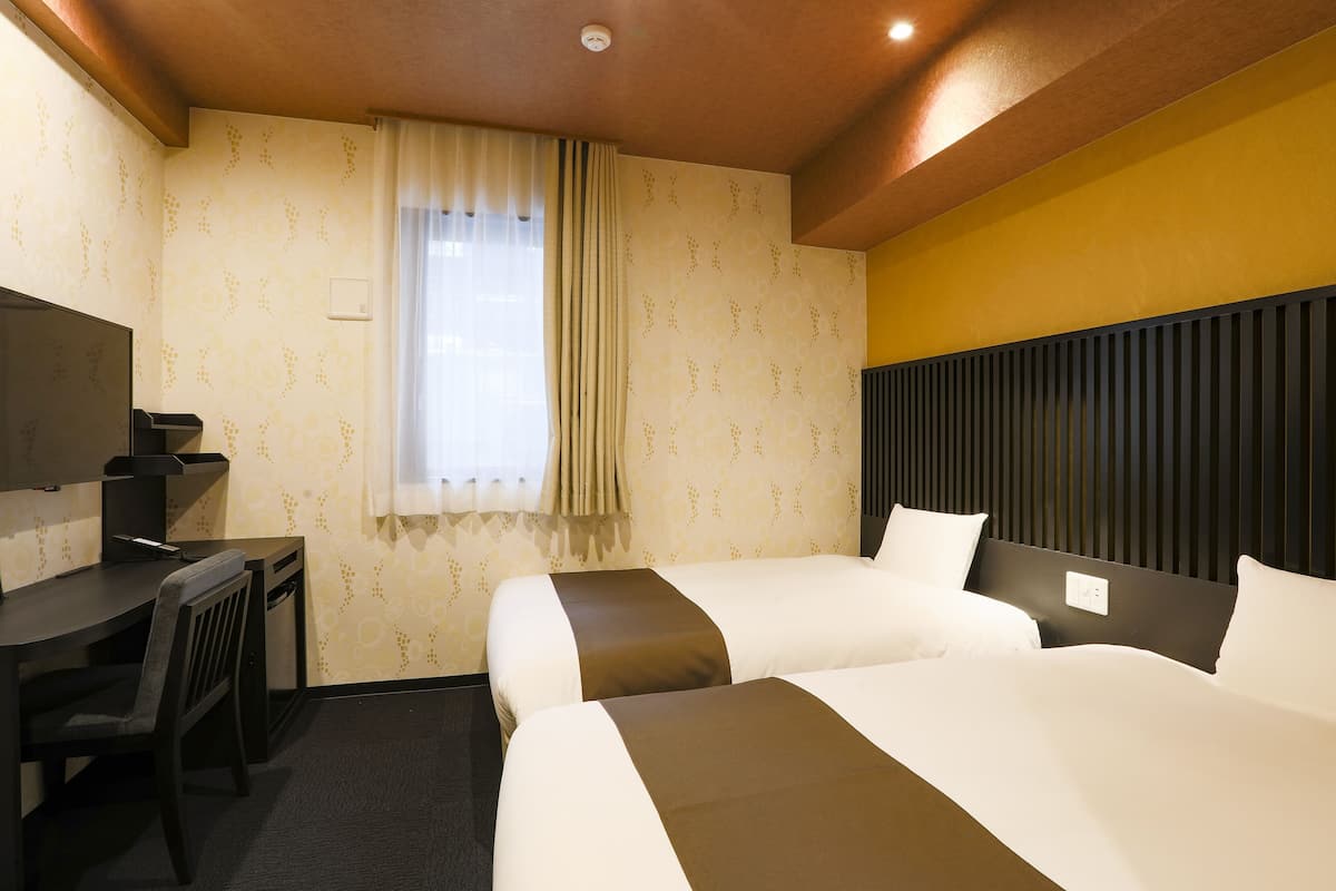 Una habitación de hotel con dos camas, un escritorio y una televisión.