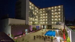 Ein mehrstöckiges Hotel mit Swimmingpool und einer Sitzgelegenheit im Freien.