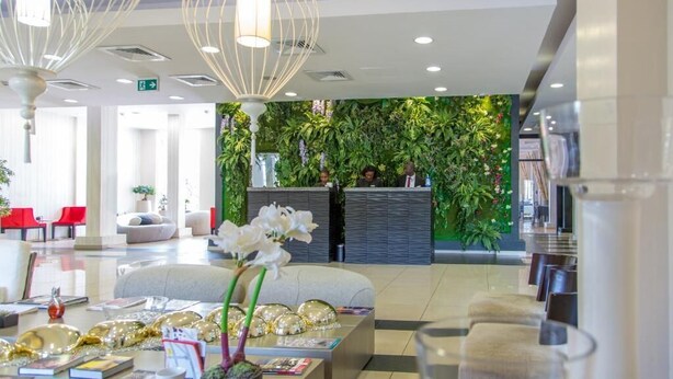 Eine moderne Lobby mit Empfangstresen, Sitzgelegenheiten und dekorativer Beleuchtung.