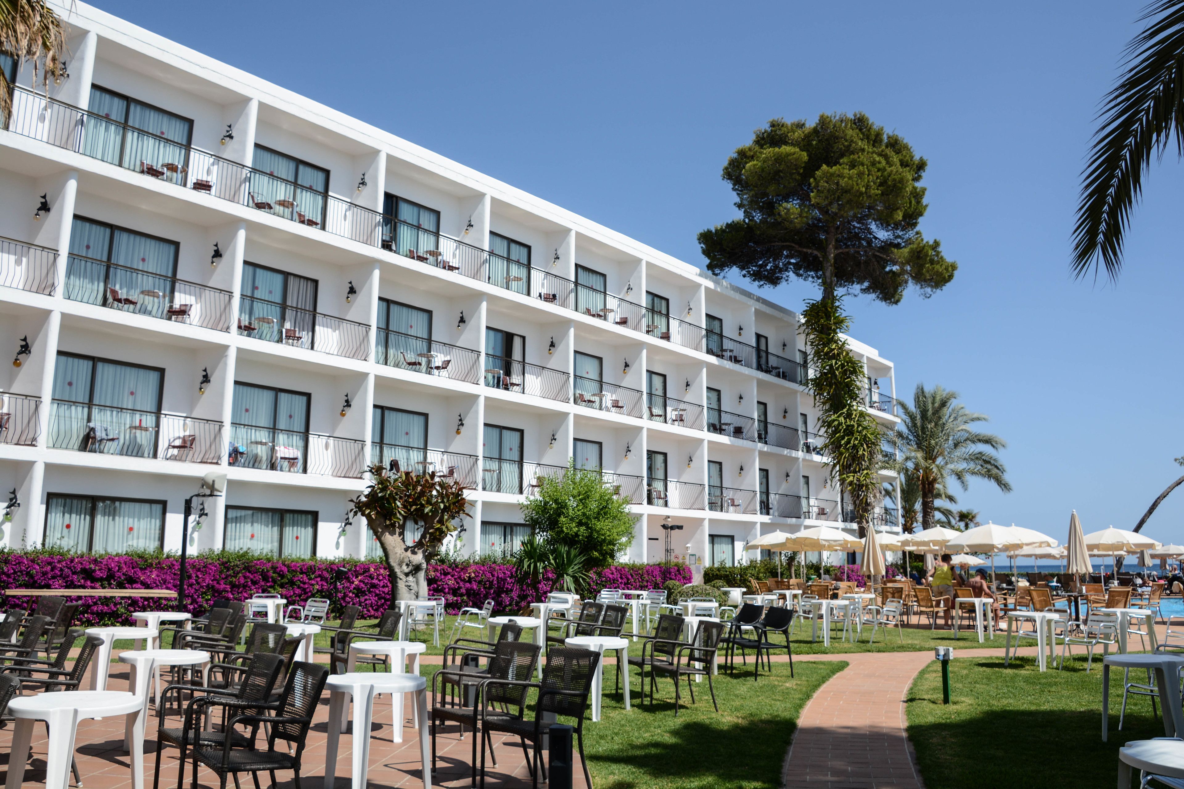 Un hotel con varios balcones, mobiliario exterior y una zona de piscina.