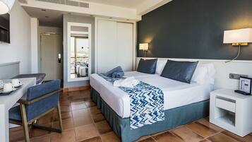 Une chambre d’hôtel comprenant un lit, une table de chevet, une chaise et un bureau avec une autre chaise.