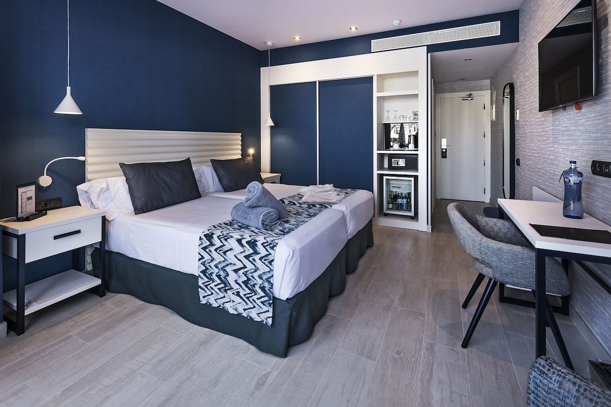 A modern bedroom with a large bed, bedside tables, a desk, and a chair.
