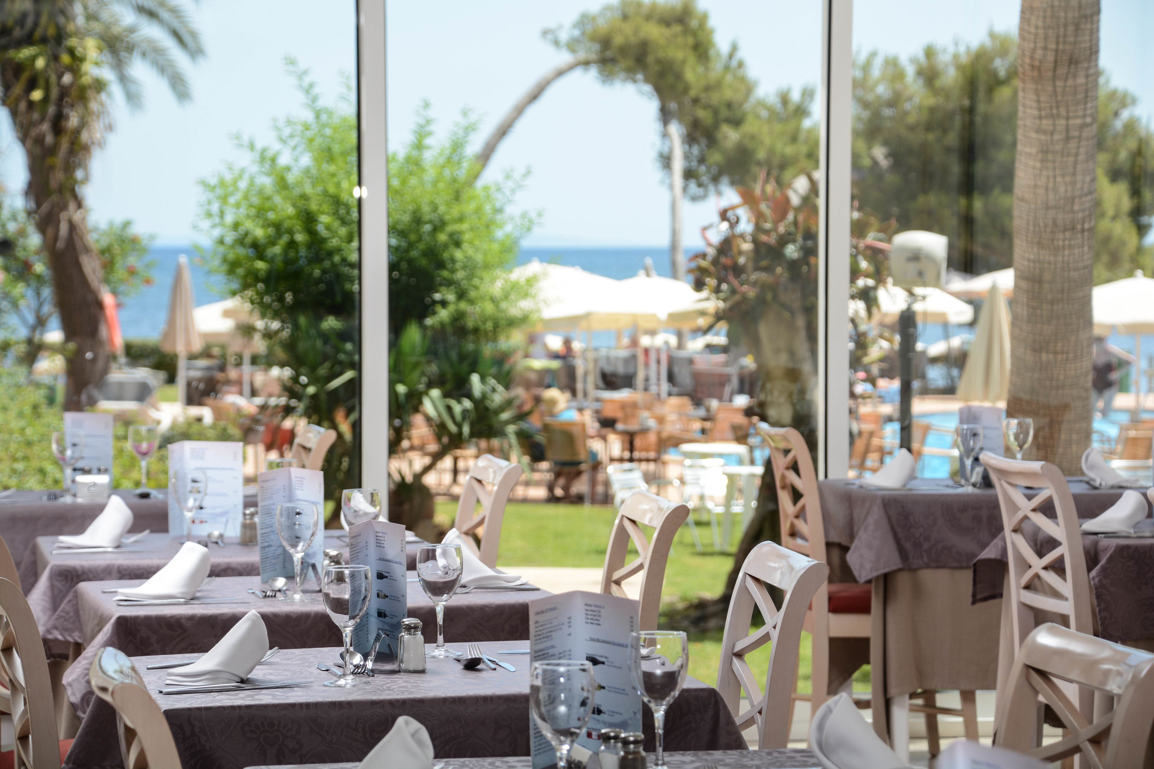 Un área de comedor al aire libre con mesas preparadas para dos, con sillas blancas y menús.