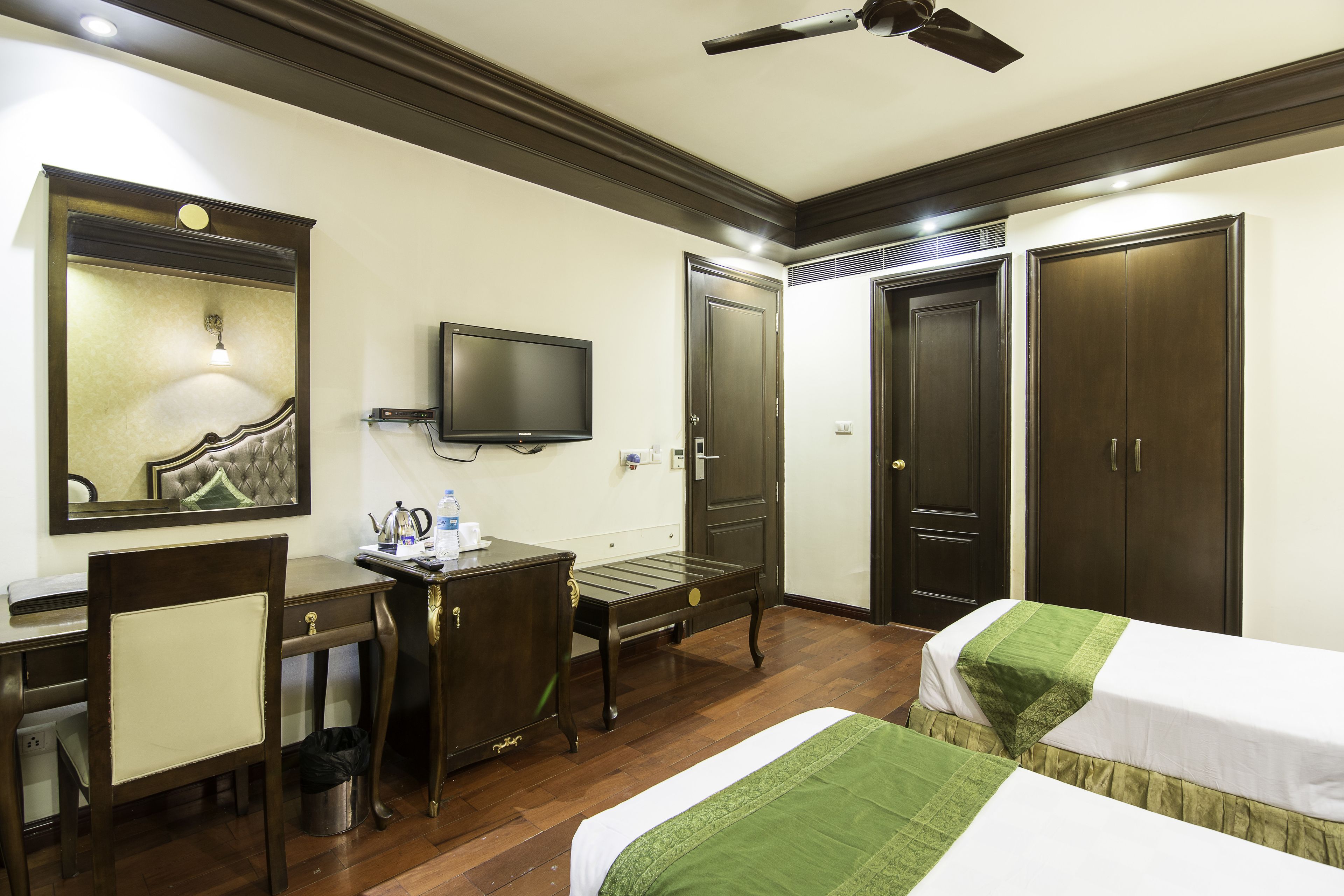 A hotel room with a desk, two beds, a TV, and a wardrobe.