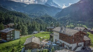 A mountain village with wooden buildings, a central courtyard, and a view of the surrounding mountains. - Restaurant - Hotel Sonnmatten (Zermatt)