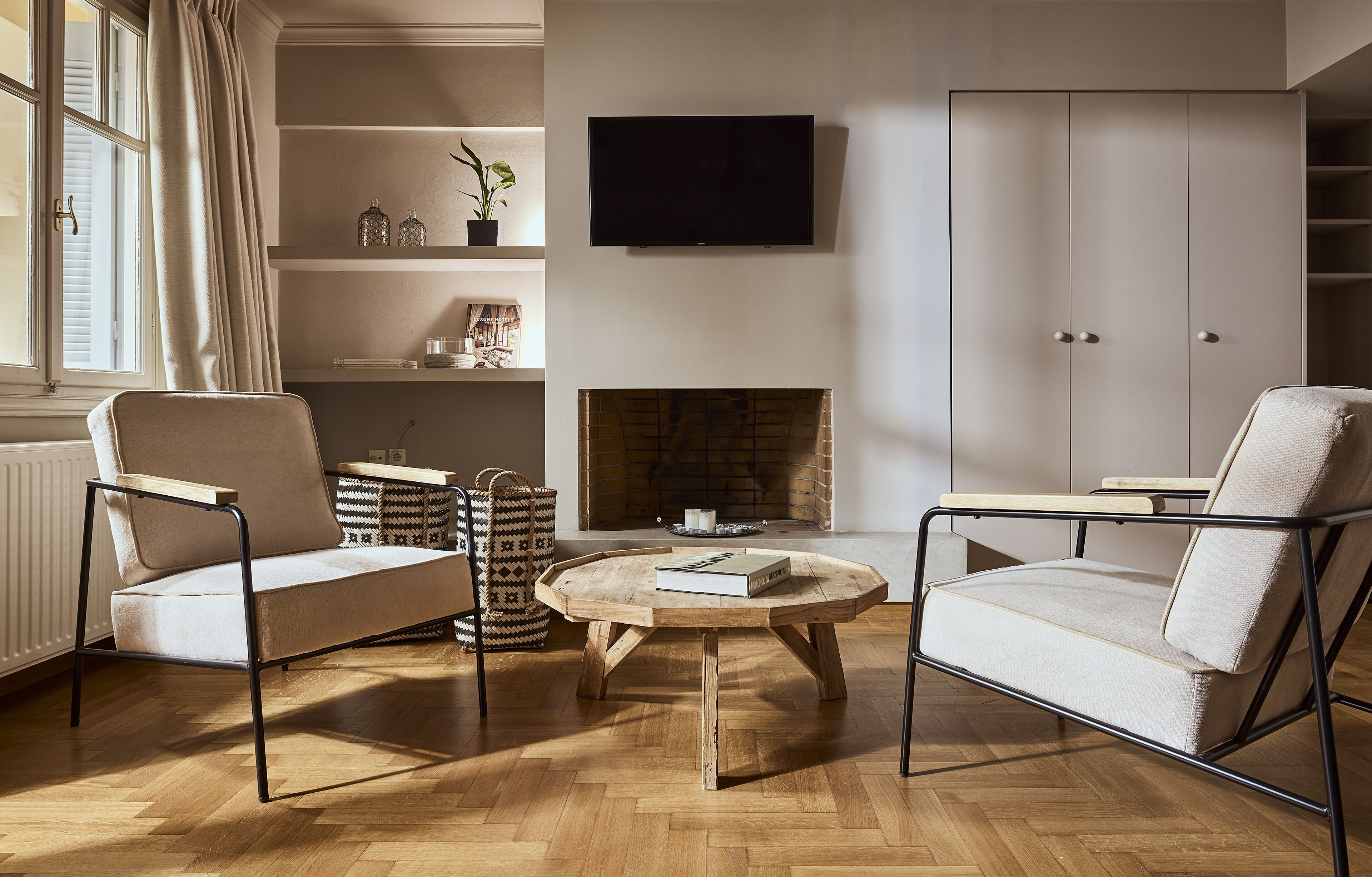 Un salon avec deux fauteuils, une table basse, une cheminée, un téléviseur et une bibliothèque.