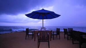 A beachside table with an umbrella, chairs, and a view of the ocean. - Sevonra Garden (Unawatuna)