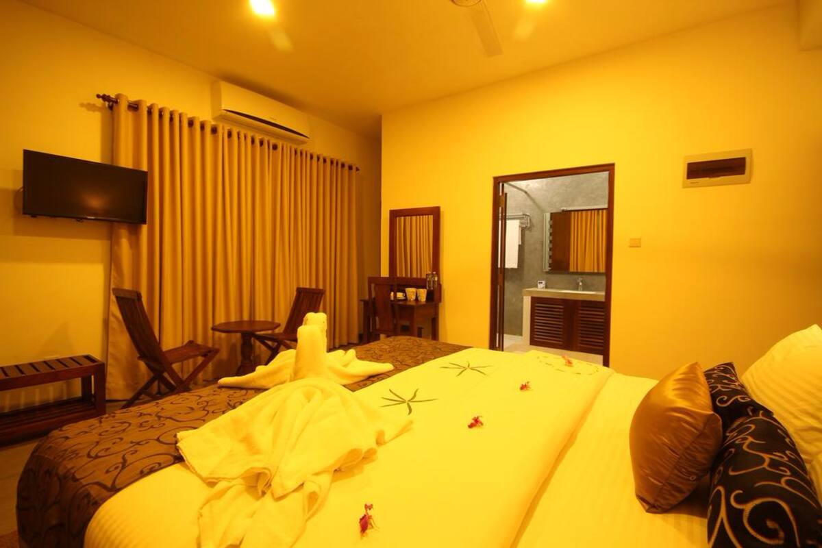 A hotel room with a bed, a TV, a desk, and a chair.