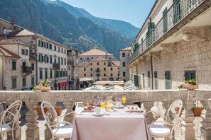 Une terrasse avec une table préparée pour le petit-déjeuner, offrant une vue sur un paysage montagneux.