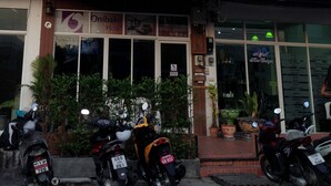 Un immeuble à plusieurs étages, sur lequel on peut lire une enseigne indiquant « Hôtel Onibaku ». Plusieurs motos sont garées devant.