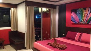 Une chambre à coucher avec un lit, un mur rouge, une fenêtre avec des rideaux et un tableau.