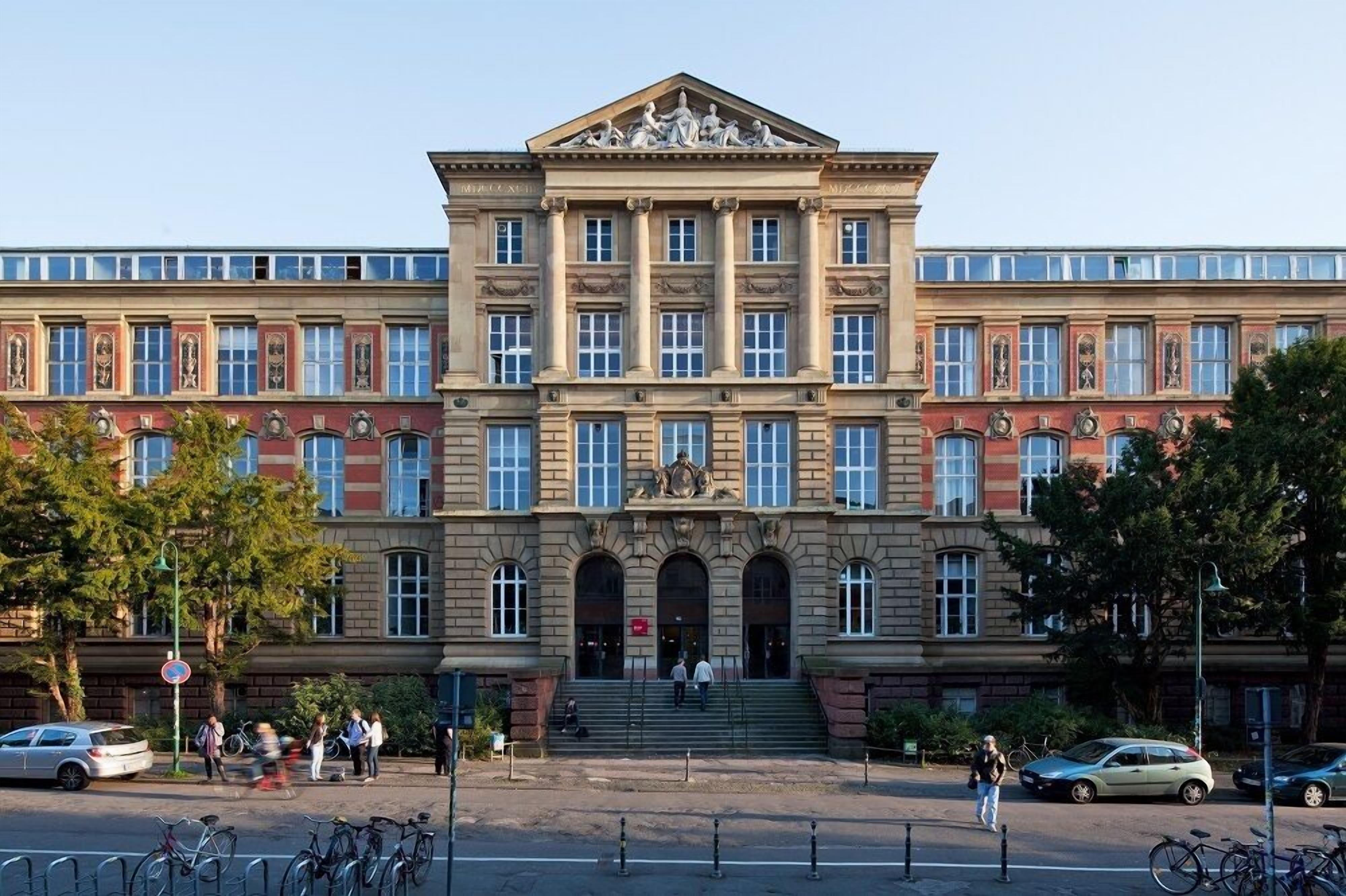 Un edificio grande e histórico con una fachada simétrica, múltiples ventanas y una entrada central con escalones.