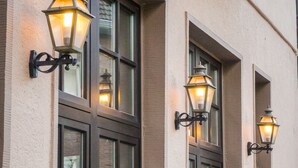 Une façade d’immeuble ornée de nombreuses fenêtres et de lanternes décoratives fixées au mur.