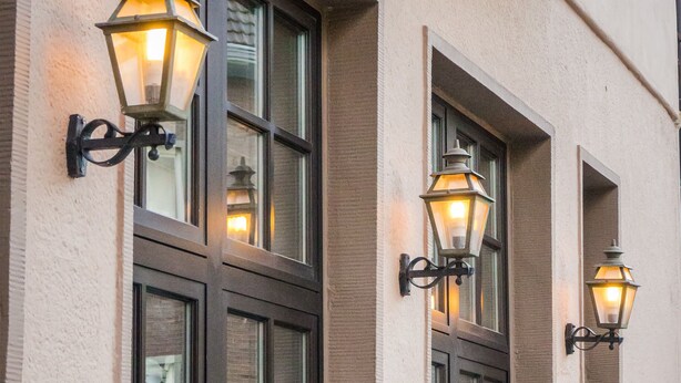 A building facade with multiple windows and decorative wall-mounted lanterns. - Hotel 3 Könige (Aachen)