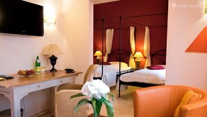 A hotel room with a bed, a desk, a chair, a TV, and a table with a vase of flowers. - Hotel 3 Könige (Aachen)
