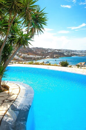 A clear blue pool with a view of a coastal town and boats in the background. - Adikri Villas & Suites (Mykonos)
