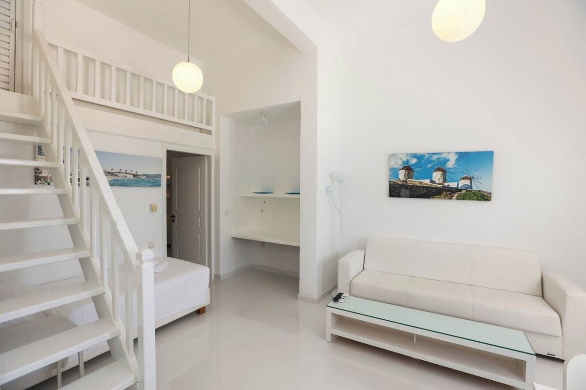 A modern, white interior with a staircase, a sofa, and a painting of windmills.