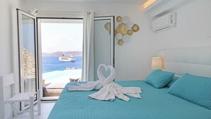 Habitación de hotel con cama, una silla blanca, vista al mar y un adorno de pared.