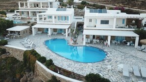 Un resort con varias construcciones blancas, una piscina central y un área de patio de piedra.