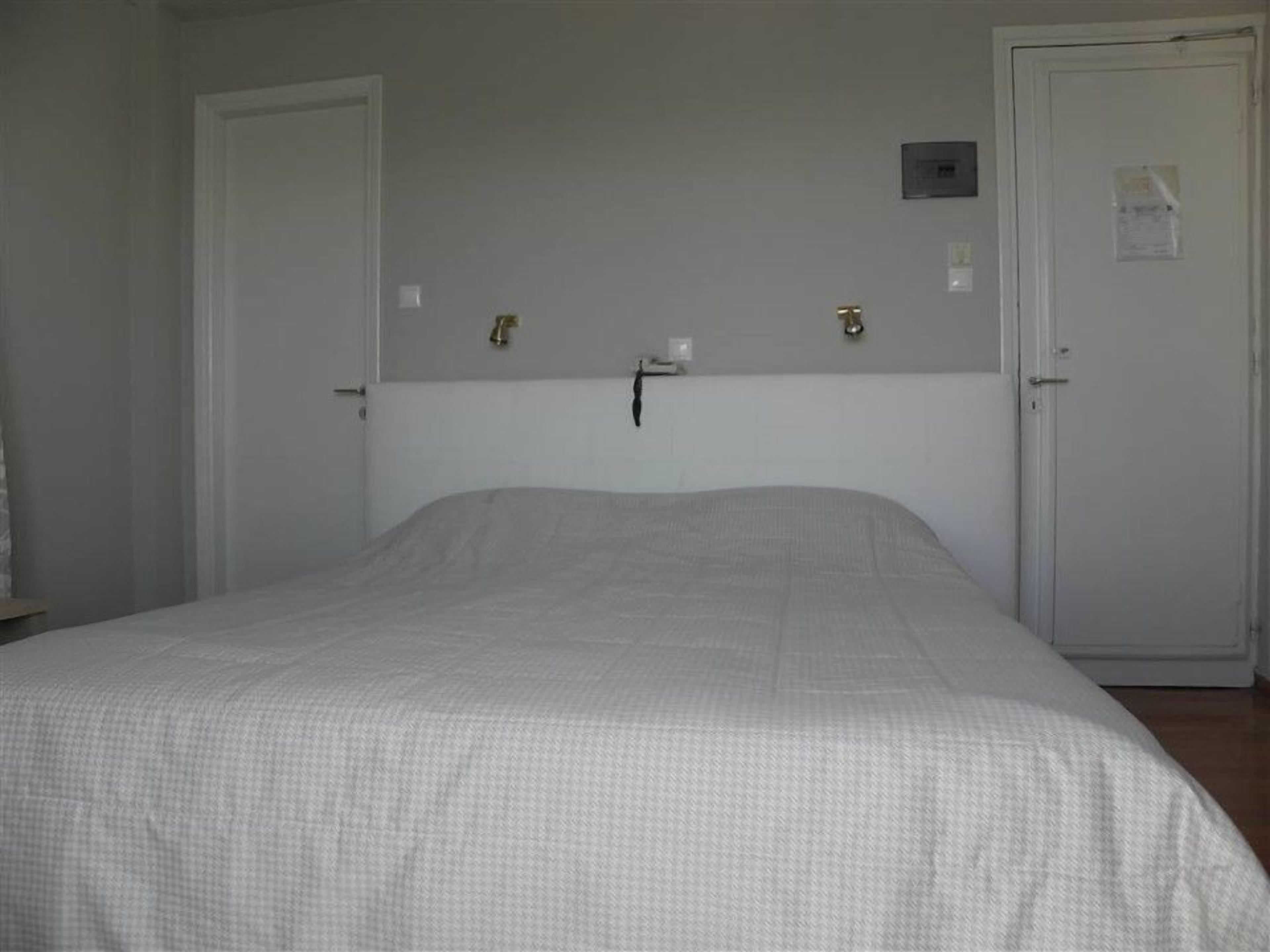 A bedroom with a single bed, two doors, and a small wall-mounted light fixture.