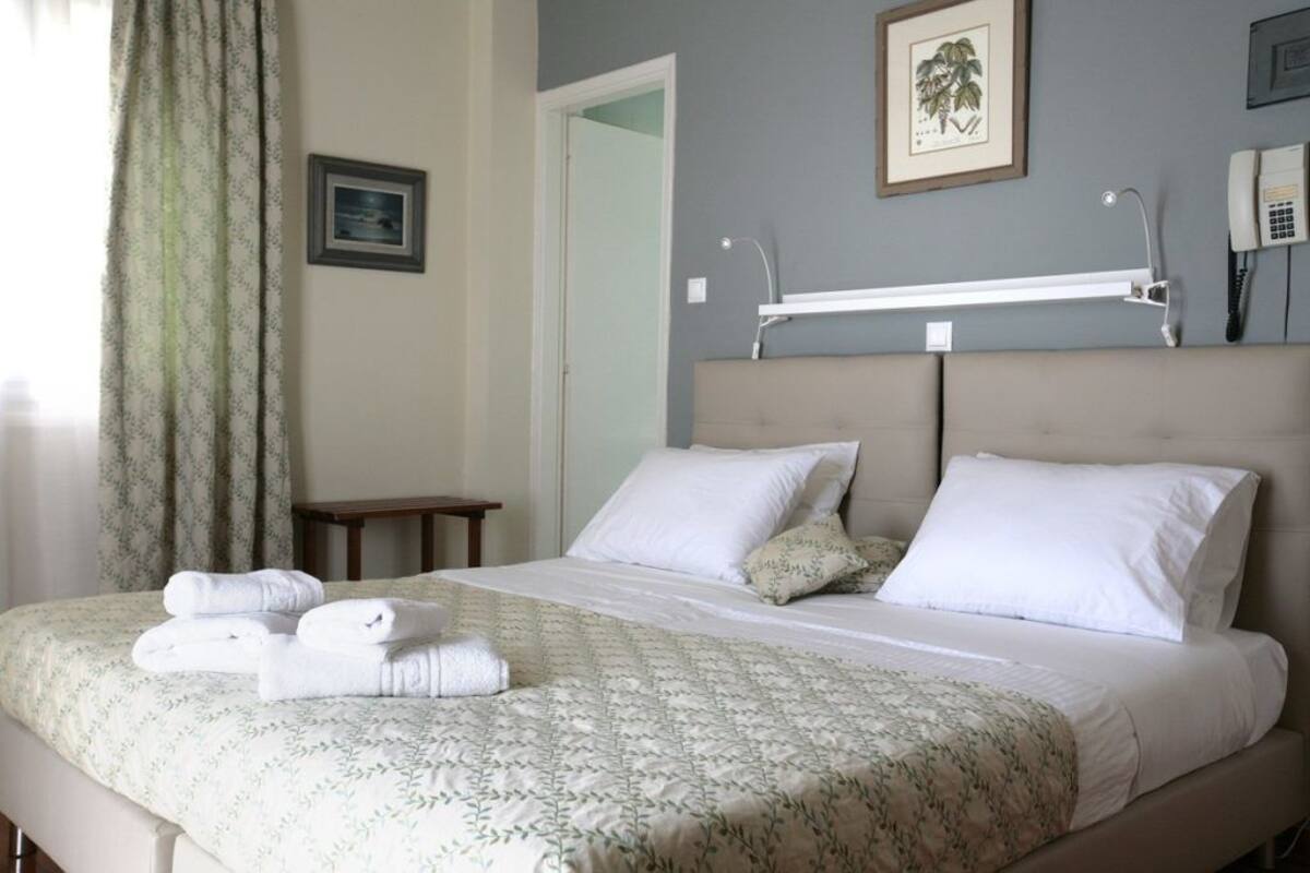 Una habitación de hotel con una cama, una mesita de noche, una lámpara y un teléfono.