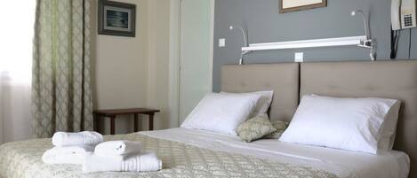 A hotel room with a bed, a bedside table, a lamp, and a telephone.
