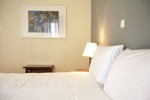 A hotel room with a bed, a nightstand, a lamp, and a framed artwork on the wall. - Hotel Theoxenia (Loutraki-Agioi Theodoroi)