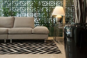 A modern living room with a sofa, a patterned rug, a lamp, and a decorative wall. - Urban Residence (Marousi)