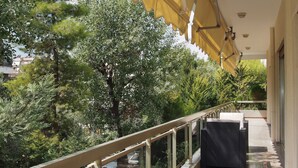 Un balcon doté d’une balustrade en verre, de mobilier d’extérieur et d’un auvent jaune.