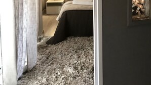 Une chambre à coucher comprenant un lit, une table de chevet, une lampe et un climatiseur fixé au mur.
