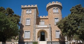 A stone building with two towers and a central entrance. - Anemi Leros Apartments (Leros)
