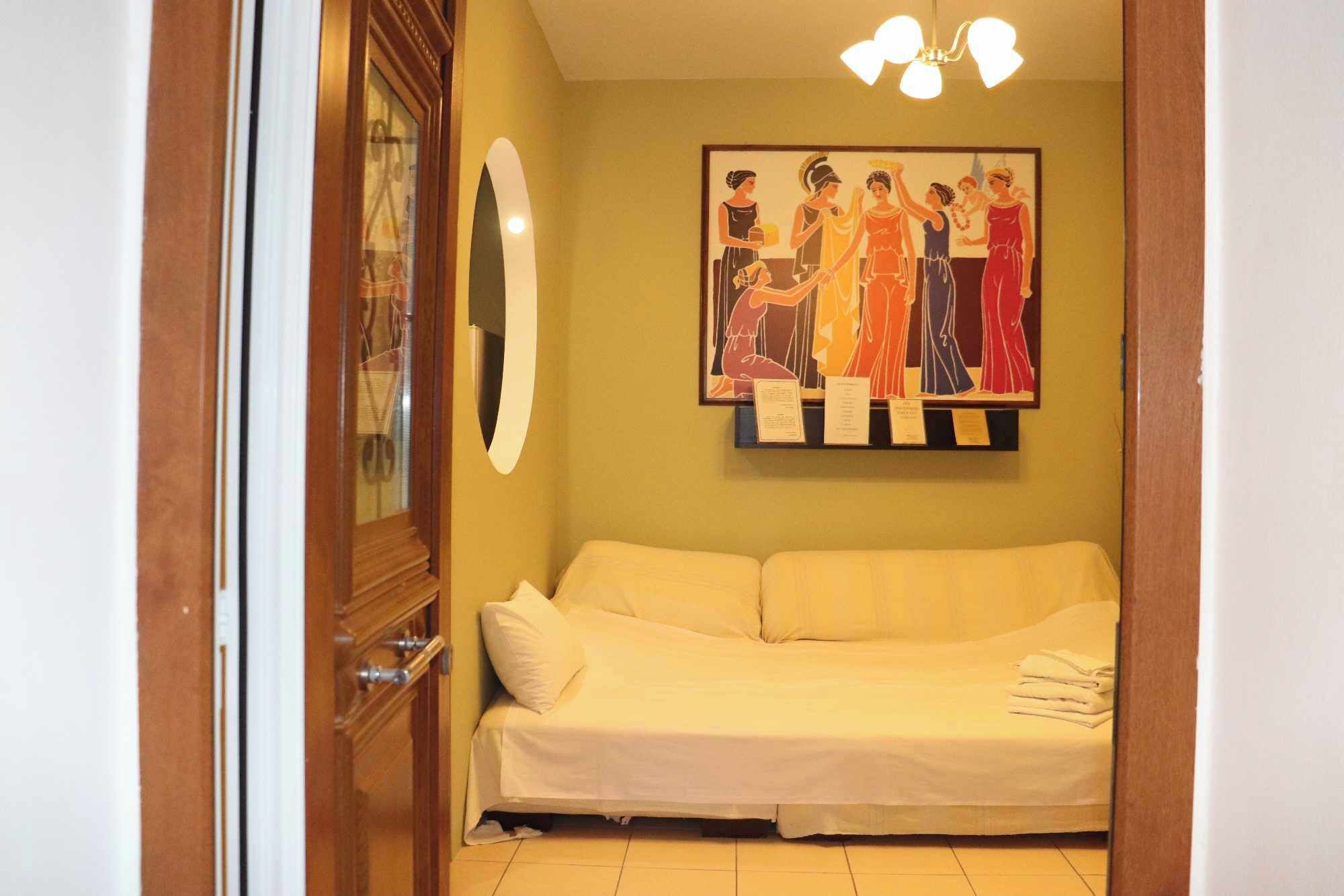 Una habitación con un sofá color beige, una obra de arte enmarcada en la pared y una puerta de madera.